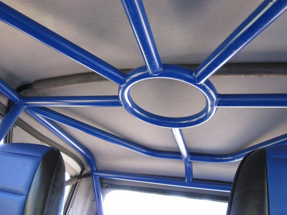 Blue roll cage structure inside a vehicle with gray headliner and blue seats