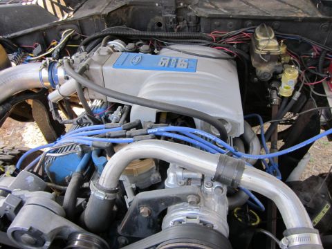 1971 Ford Bronco - Close-up view of a modified engine bay a 5.0 liter intake manifold and blue spark plug wires.