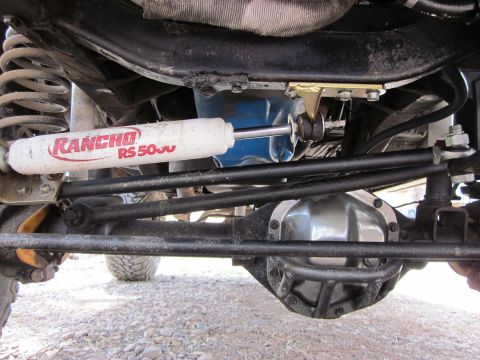 1971 Ford Bronco - Close-up of the front axle and steering stabilizer on a vehicle.