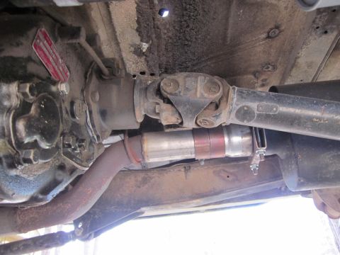 1971 Ford Bronco - Close-up of the underbody drivetrain and exhaust components, including a visible red tag on the transmission.