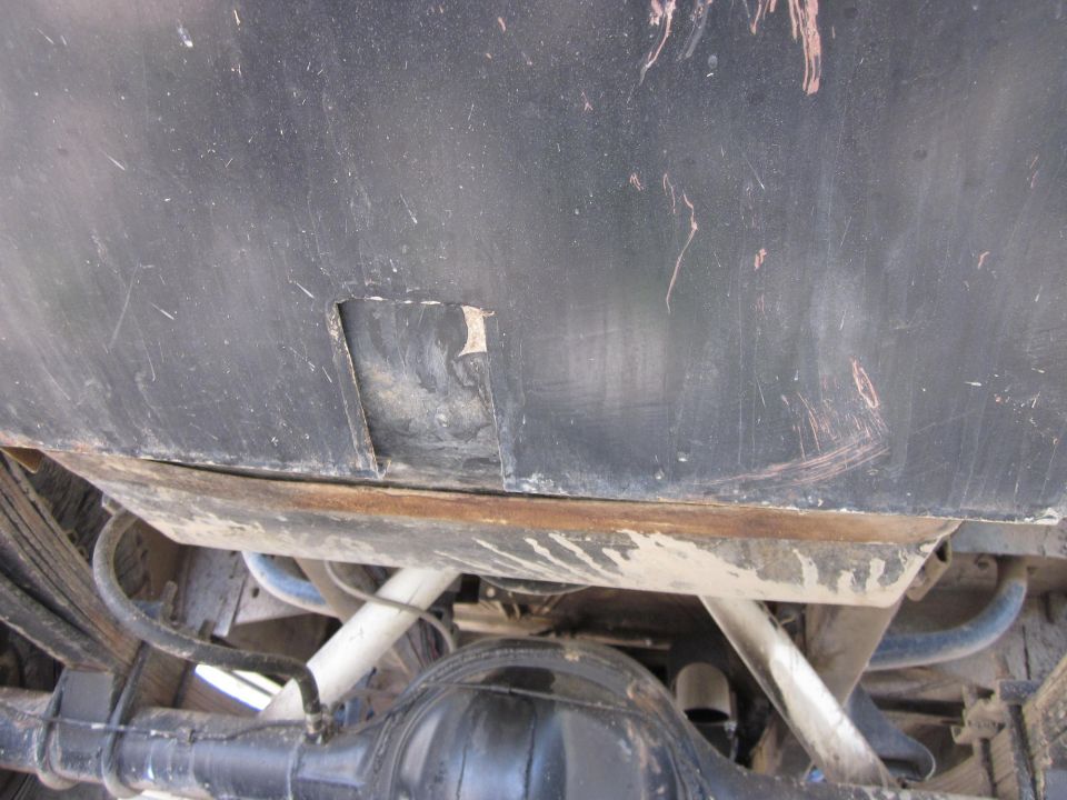Underside of a vehicle showing the rear axle, leaf springs, and fuel tank. There's a SuperMotors logo in the corner