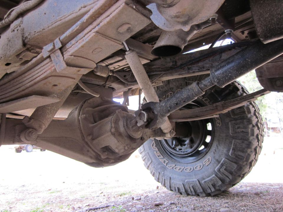 Underside view of a 4x4's rear axle, leaf springs, driveshaft, and tire