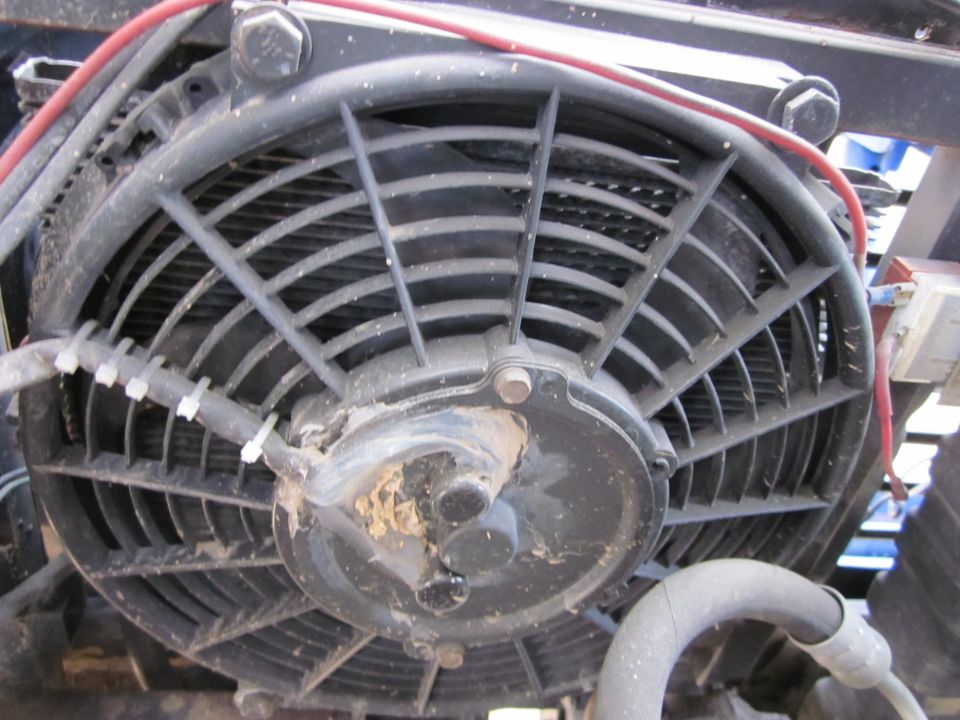 Electric cooling fan with black blades and a central motor housing, wires attached