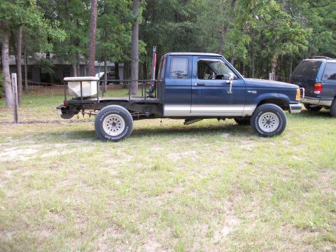 1994 Ford Explorer - This blue pickup truck features a flatbed conversion and a utility box, with a visible 1994 badge.