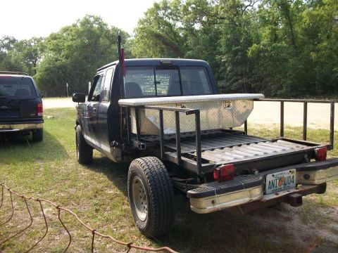 1994 Ford Explorer - A modified pickup truck with a flatbed and a rifle mounted in the bed is seen next to an SUV.
