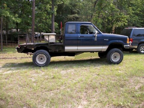1994 Ford Explorer - Side view of a blue pickup truck with a custom flatbed and toolboxes, parked outdoors.