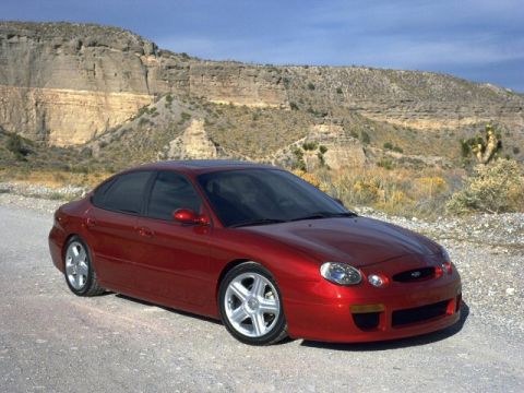 1993 Ford Taurus - A red sedan with a distinctive body style is parked outdoors.