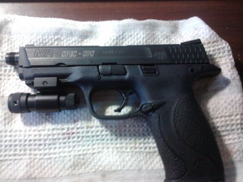 1989 Ford Bronco - A close-up view of a Smith & Wesson M&P pistol equipped with a mounted flashlight.