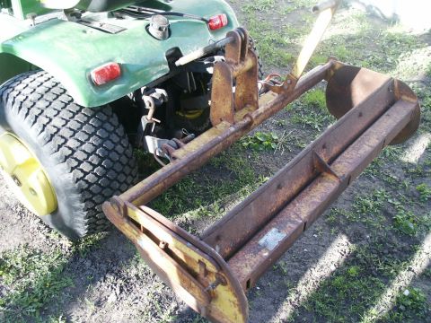 1966 Ford Bronco - A green tractor is shown from the rear, attached to a rusty yellow implement.