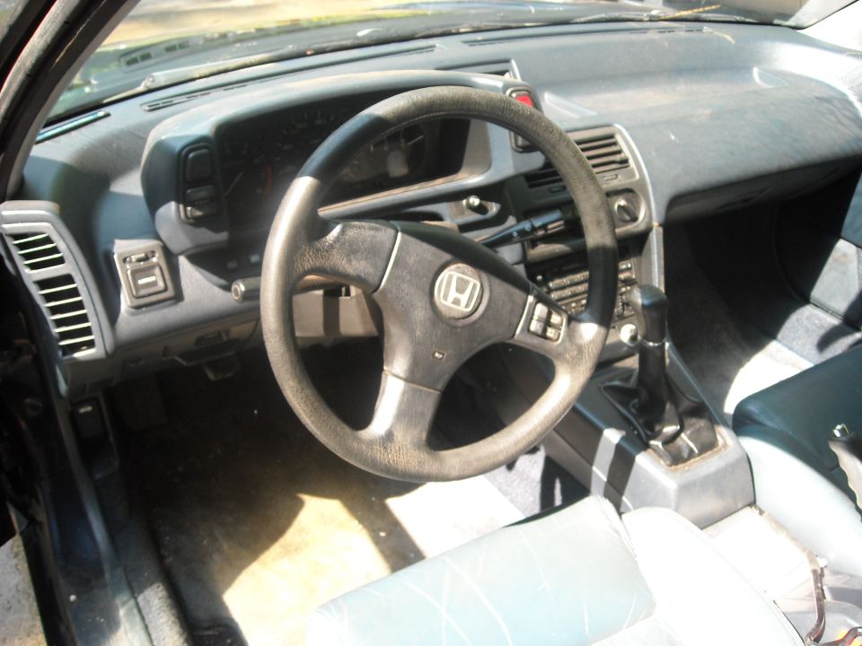 Interior shot of a Honda Prelude, showing the steering wheel, dashboard, and gear shifter