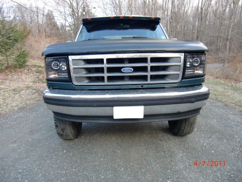 1993 Ford Bronco - This Ford truck, likely from the early to mid-1990s, is shown head-on with a prominent grille and clear license plate area.