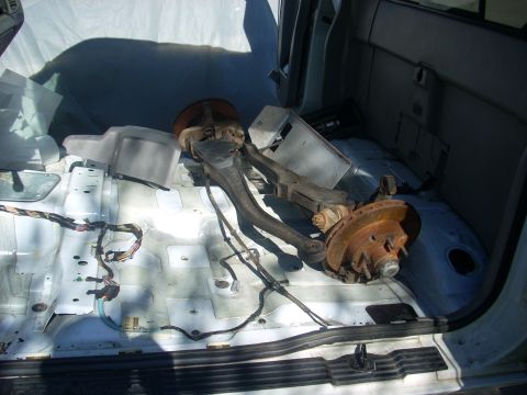 1992 Ford Ranger - Pickup truck bed contains disassembled suspension parts like control arms and brake rotors.
