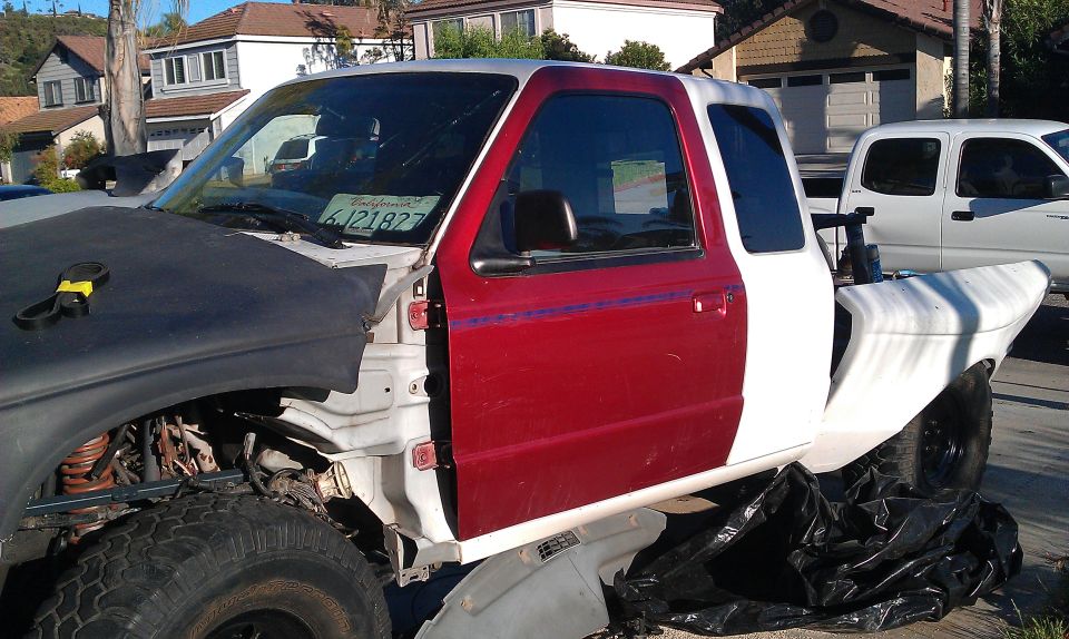 1992 Ford Ranger cab, red door, white fender, black hood, California license plate 6J21827. Another white truck is parked behind