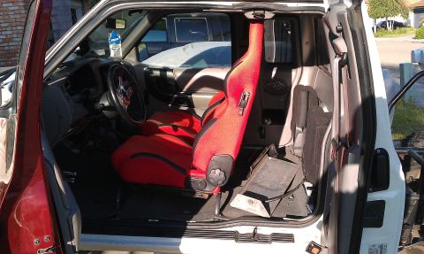 1992 Ford Ranger - The interior of a truck is shown, custom red racing seats and a visible roll cage structure.