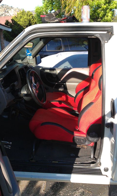 1992 Ford Ranger - The interior of a truck features custom red and black racing seats and a modified steering wheel.