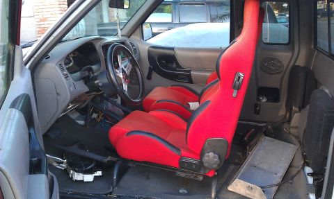 1992 Ford Ranger - The interior of a pickup truck shows custom red racing seats and an aftermarket steering wheel.