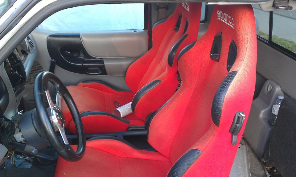 Interior view of a vehicle with red racing seats and a custom steering wheel