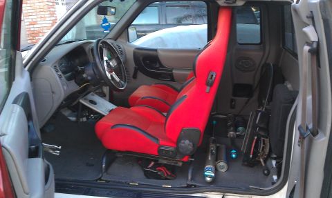 1992 Ford Ranger - The interior of a 1992 Ford Ranger features bright red racing seats and a custom steering wheel, with various parts visible on the floor.