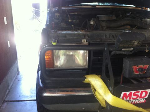 1990 Ford Bronco - The front of a 1990 Ford Bronco is visible with its hood open, revealing the engine compartment and a winch mounted on the front.
