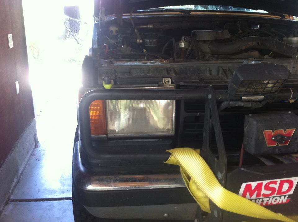 Front view of a 1990 Ford Bronco with hood open, showing engine and winch