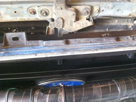 1990 Ford Bronco - The image shows the upper part of a vehicle's front, including the hood latch and a portion of the grille area.