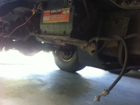 1990 Ford Bronco - The underside of a vehicle is captured, revealing the battery and suspension components.