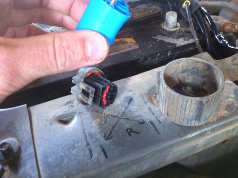 1990 Ford Bronco - A hand connects a blue electrical connector to a socket, revealing red wires within the connector.