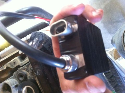 1990 Ford Bronco - A hand holds a black electronic component with visible wires and metal connectors, possibly part of a vehicle's electrical system.