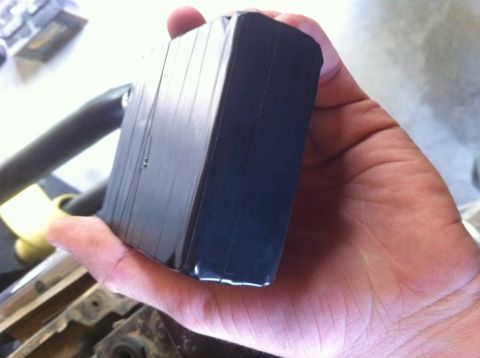 1990 Ford Bronco - A hand holds a black electronic component with ribbed sides, possibly a module or control unit.