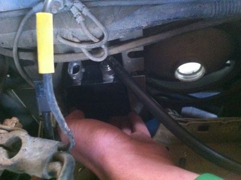 1990 Ford Bronco - A hand is visible working on the undercarriage of a vehicle, with various hoses and metal parts in view.