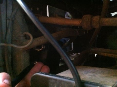 1990 Ford Bronco - Close-up view of a vehicle's undercarriage, showing various mechanical components and a hand interacting with them.