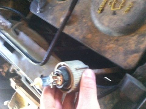 1990 Ford Bronco - Close-up of a hand holding a light bulb socket, likely for a vehicle repair.