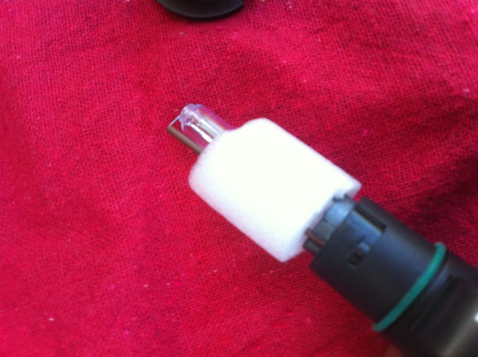 Close-up of a light bulb filament and its socket, resting on a red textured surface