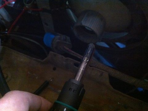 1990 Ford Bronco - Close-up of a hand holding a bulb, possibly for a vehicle's headlight system.