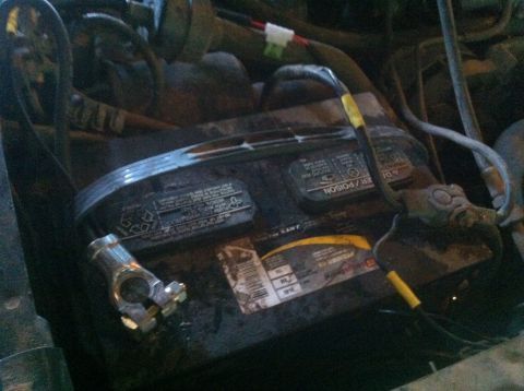 1990 Ford Bronco - Close-up of a car battery and its associated wiring, with a loose terminal clamp.