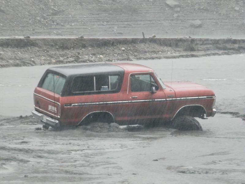 Red 1978 Ford Bronco stuck in mud, side view