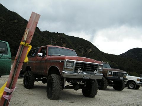 1978 Ford Bronco - A lifted 1978 Ford Bronco is parked in a dusty lot with mountains in the background.