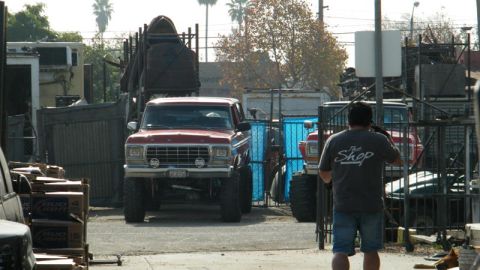 1978 Ford Bronco - A red Ford truck is parked in an outdoor lot with other vehicles and industrial equipment.