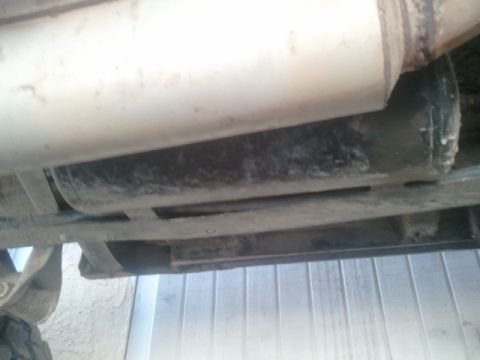 1979 Ford Bronco - Close-up view of the undercarriage and exhaust system of a vehicle, with visible signs of wear and tear.