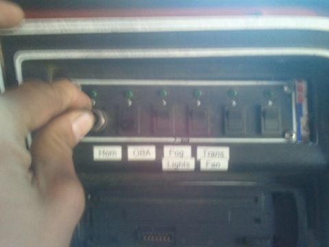1979 Ford Bronco - A hand adjusts a switch on a custom panel with labels for various vehicle functions.