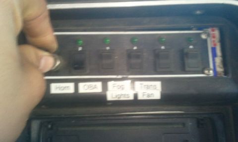 1979 Ford Bronco - A hand adjusts a knob on a dashboard switch panel labeled for various accessories like Horn and Fog Lights.