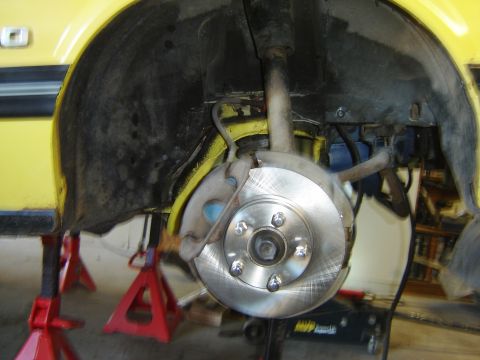 1979 Ford Mustang - Close-up of a yellow car's front wheel brake assembly, showing the rotor and caliper.