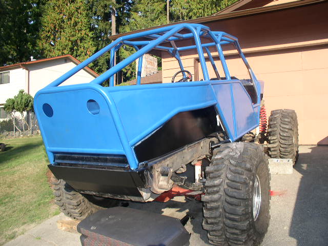 Bright blue chopped Ford Bronco trail rig with exterior tube cage in a driveway