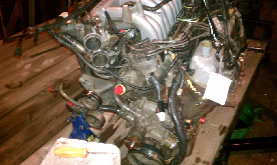 Engine assembly on a wooden surface, with a screwdriver nearby