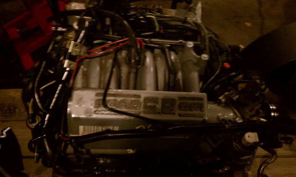 Engine with visible wiring and intake manifold. Text visible on a component