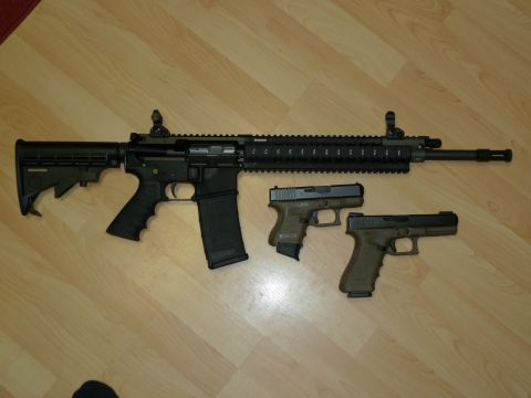 1992 Ford Mustang - Three firearms are laid out on a wooden floor: an AR-15 style rifle and two handguns.