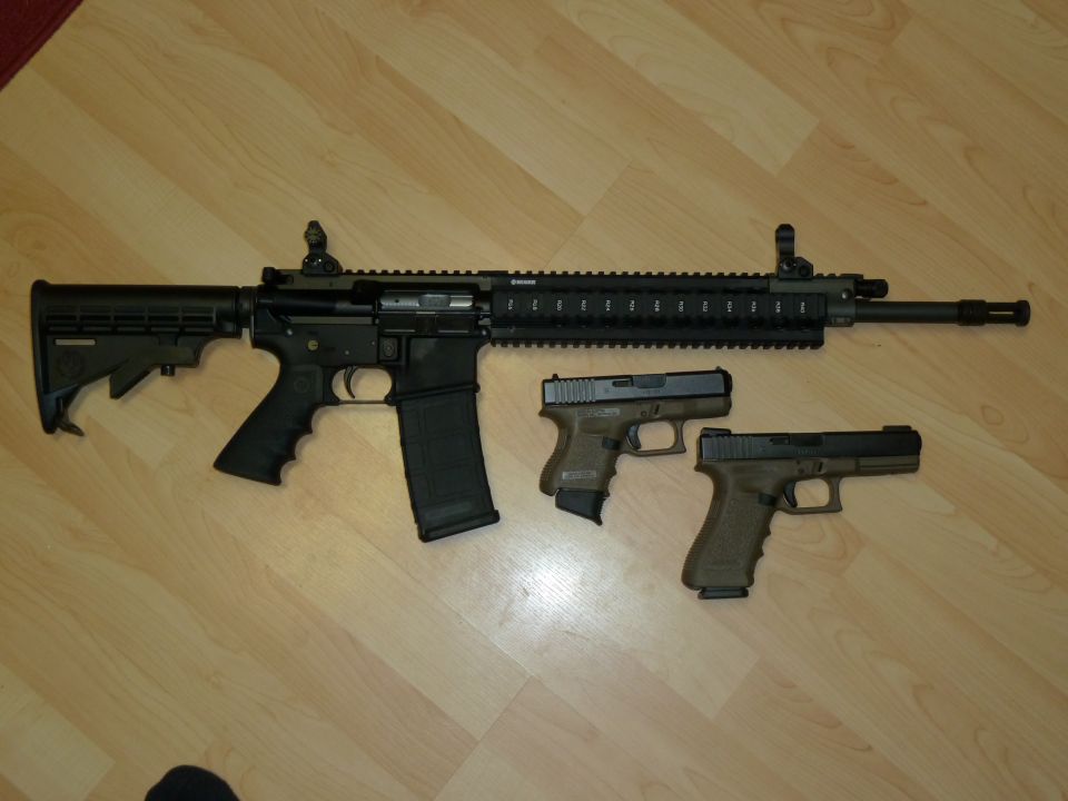 AR-15 style rifle with a tan pistol grip and magazine, next to two tan Glock pistols