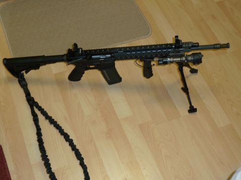 1992 Ford Mustang - A tactical rifle with accessories is displayed on a light-colored wooden floor.