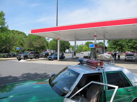 1991 Ford Crown Victoria - Police car interior visible at a gas station with multiple other vehicles present.