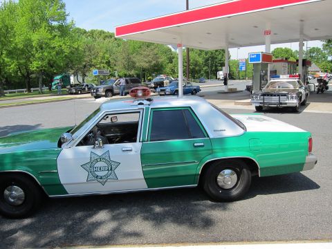 1991 Ford Crown Victoria - A 1991 Ford Crown Victoria, marked as Sheriff's vehicle, is parked at a gas station with other cars in the background.